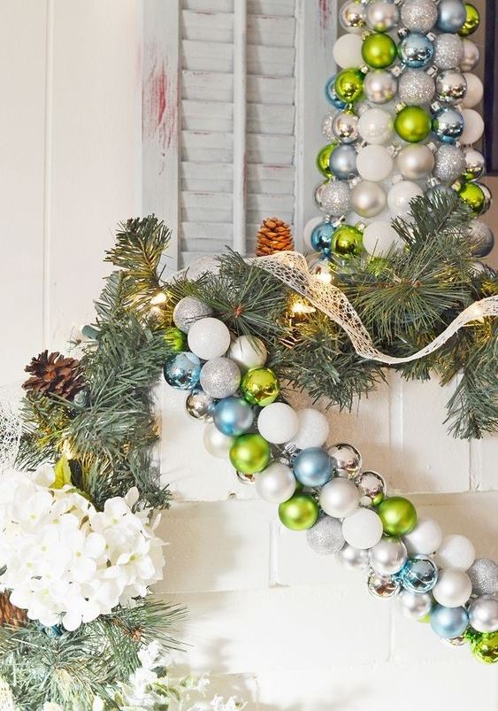a green, white and blue Christmas ornament garland over the fireplace for cool holiday decor