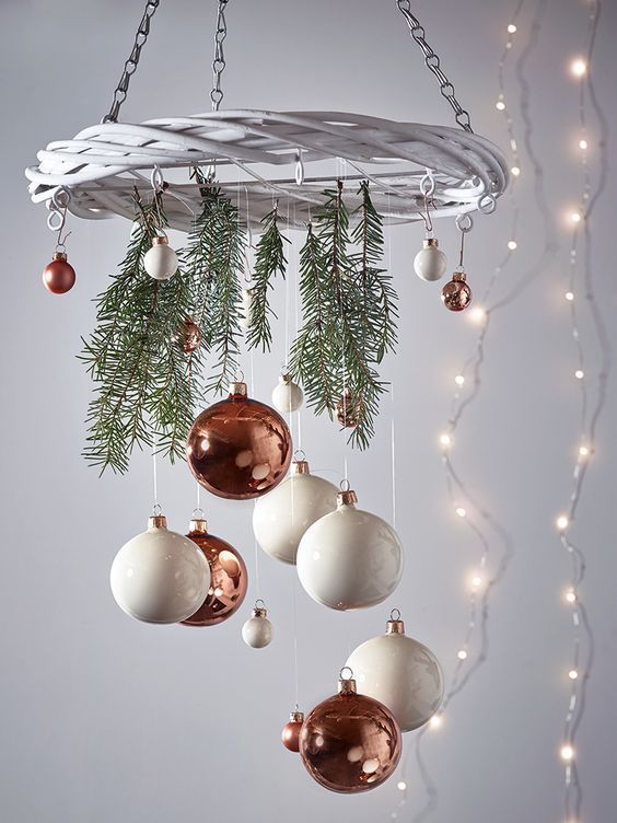 a holiday chandelier of a white wreath, evergreens and small copper and white ornaments for Christmas