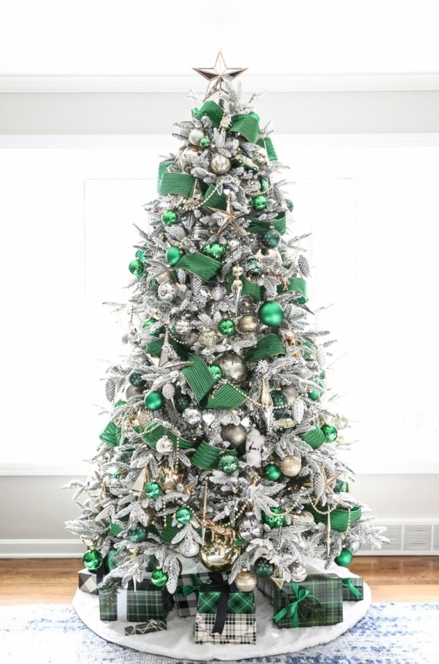 a jaw-dropping flocked Christmas tree styled with emerald ribbons and ornaments, gold and silver ornaments and beads and a silver star tree topper
