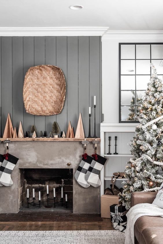 a laconic Scandi-inspired Christmas mantel with wooden and bottle cleaner trees, plaid stockings and candles in tall candleholders