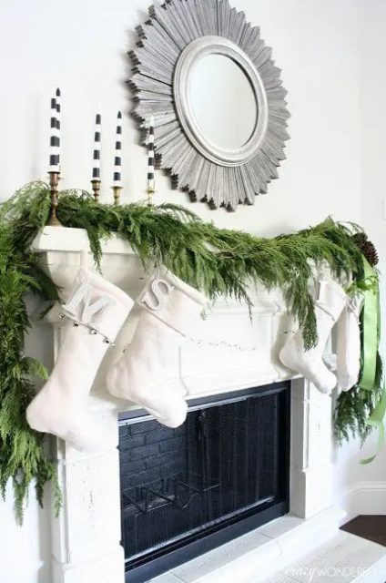 a lush evergreen garland, creamy stockings and striped candles make up a modern look with a rustic feel