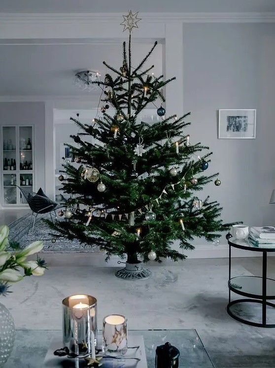 a modern Scandi Christmas tree with navy, silver, green and clear ornaments plus lights and buntings is a beautiful idea