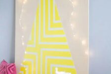 a neon yellow geometric Christmas tree on a plywood sheet with lights around for a colorful space