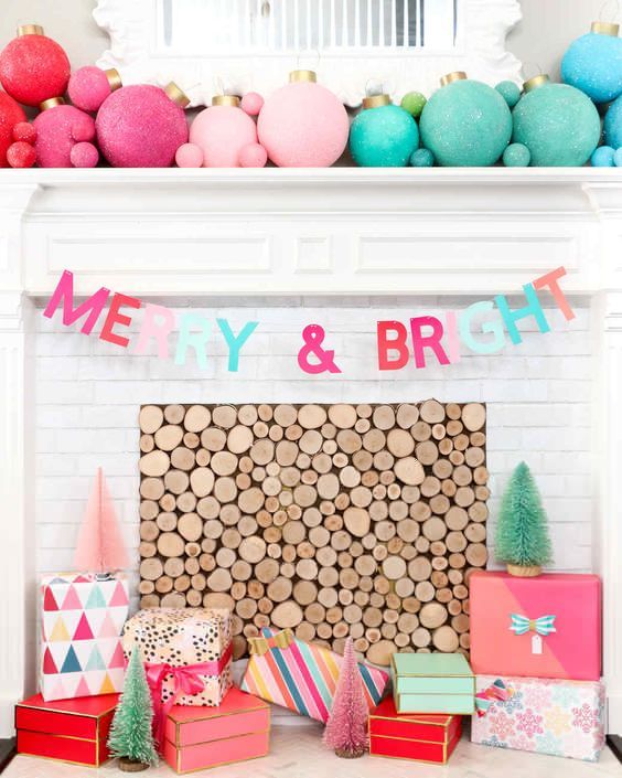 a non-traditional and bold Christmas mantel with large and small color block Christmas ornaments, a matching letter banner and gift boxes