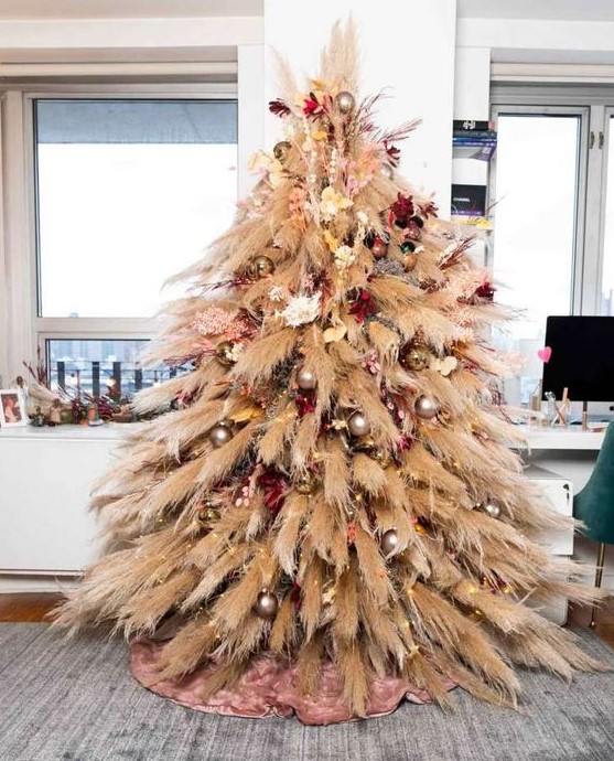 a pampas grass Christmas tree with neutral, pink and burgundy blooms and metallic ornaments plus lights