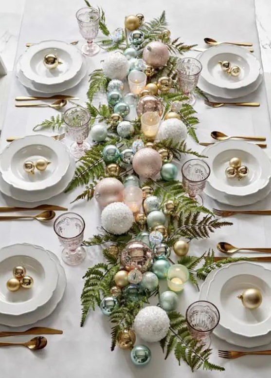 a pretty pastel Christmas tablescape with fern leaves, green and metallic ornaments, chic plates and gold cutlery
