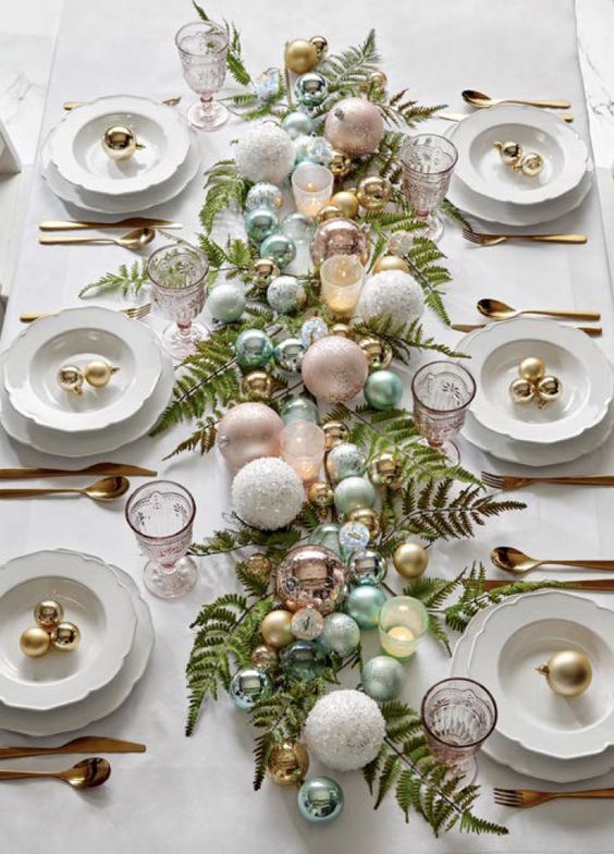 a pretty pastel Christmas tablescape with fern leaves, pastel and metallic ornaments, chic plates and gold cutlery
