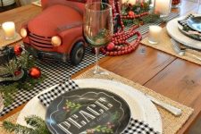 a retro Christmas table with buffalo check linens, black and white plates, a red truck with bottle brush Christmas trees and red ornaments