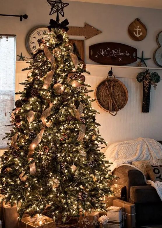 a rustic luxe Christmas tree with snowy and gilded pinecones, burlap ribbons, large metal ornaments and lots of lights