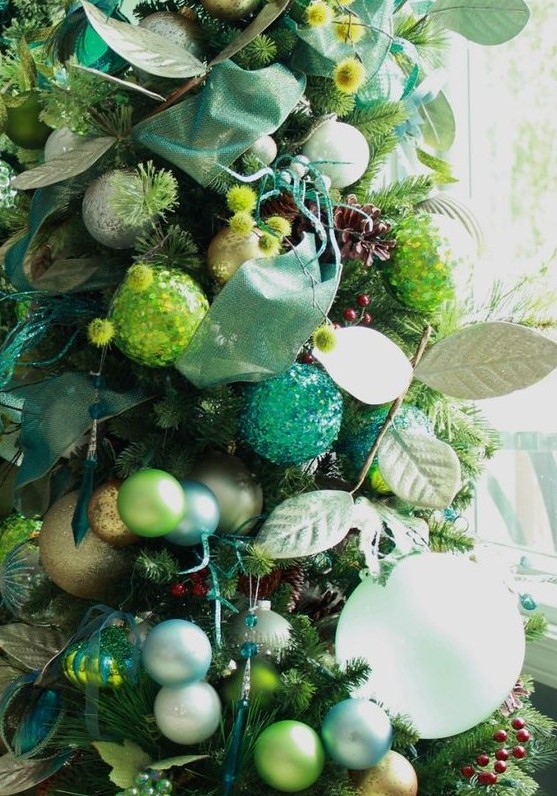 a shiny glam Christmas tree with emerald and neon green ornaments, silver and white ones, green ribbons and faux foliage