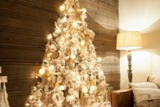 a shiny wall-mounted Christmas tree made with lights on the contour and with lots of silver, pearly and white ornaments inside