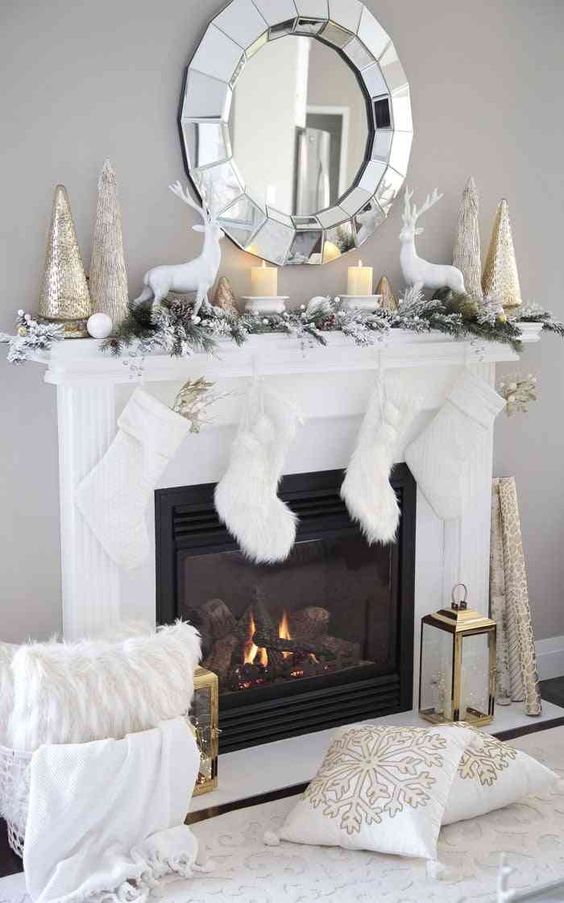 a snowy Christmas mantel with deer, candles, shiny Christmas trees, a snowy evergreen garland with pinecones