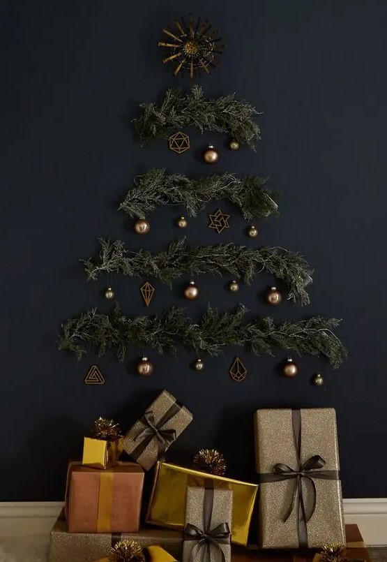 a stylish wall-mounted Christmas tree on a black wall of evergreens, lights and brass ornaments