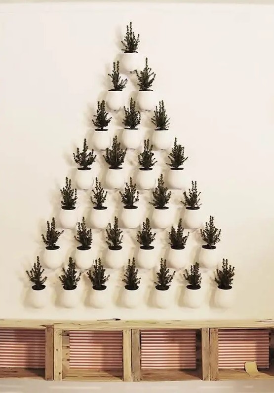 a super creative Christmas tree formed of potted evergreens that are attached to the wall