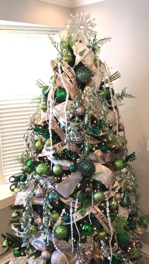 a super shiny and glam Christmas tree decorated with white and green ornaments of various shades, ribbons, lights, twigs and beads