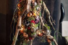 a unique alternative to a usual Christmas tree with gold, copper, silver, purple and red ornaments, lights, moss and pinecones is a bold idea