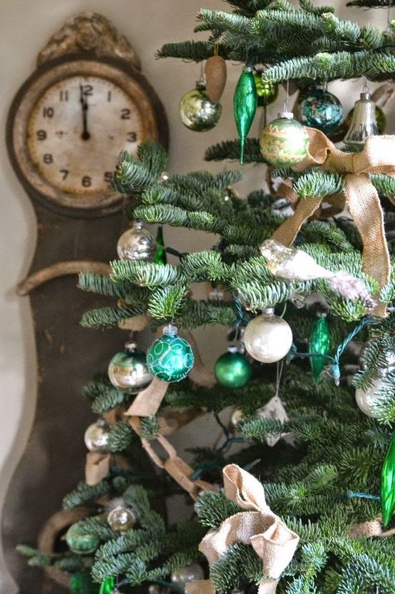 a vintage rustic Christmas tree decorated with light and emerald green ornaments, burlap bows and chain garlands is chic