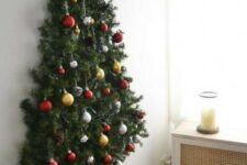 a wall-mounted Christmas tree with pine garlands and Christmas ornaments plus pinecones looks natural and cool