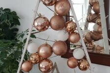 a white frame Christmas tree with threads, copper, rose gold and white ornaments hanging plus a silver star is cool
