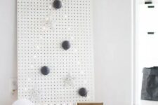 a white pegboard with a Christmas tree lined out with lights and with some ornaments