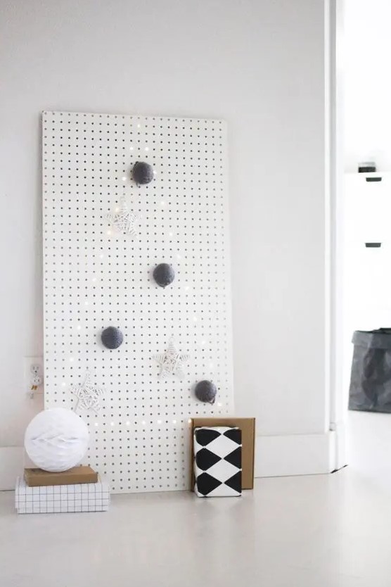 a white pegboard with a Christmas tree lined out with lights and with some ornaments