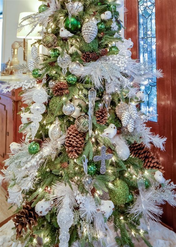 a woodland Christmas tree with green, silver and white ornaments, snowflakes, feathers, birds and pinecones is a bold and cool idea
