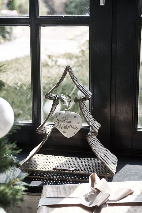 a woven tabletop Christmas tree with a single white heart ornament and some eucalyptus is a stylish rustic decoration