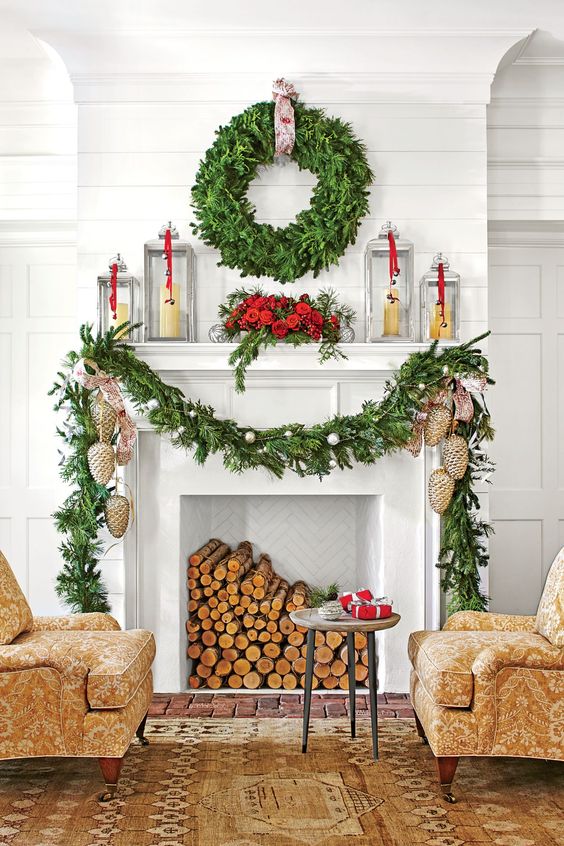 an elegant Christmas mantel with an evergreen garland, ornaments, pinecone ornaments, candles in candle lanterns and an evergreen wreath
