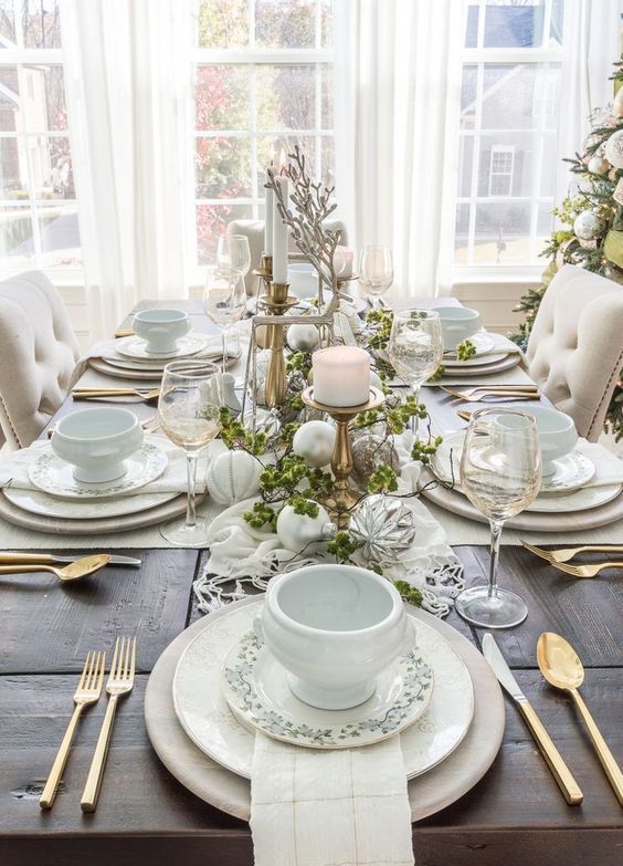 an ethereal Christmas tablescape with neutral and metallic ornaments, neutral porcelain, greenery, candles and white porcelain