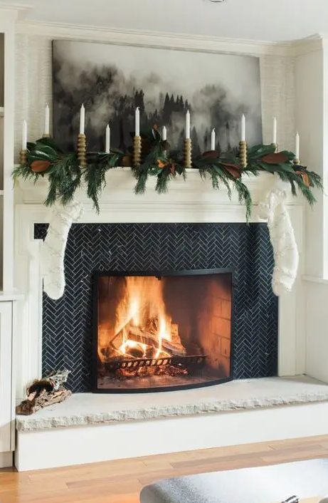 an evergreen and magnolia garland with lots of candles  and fluffy white stockings are enough to create a festive look