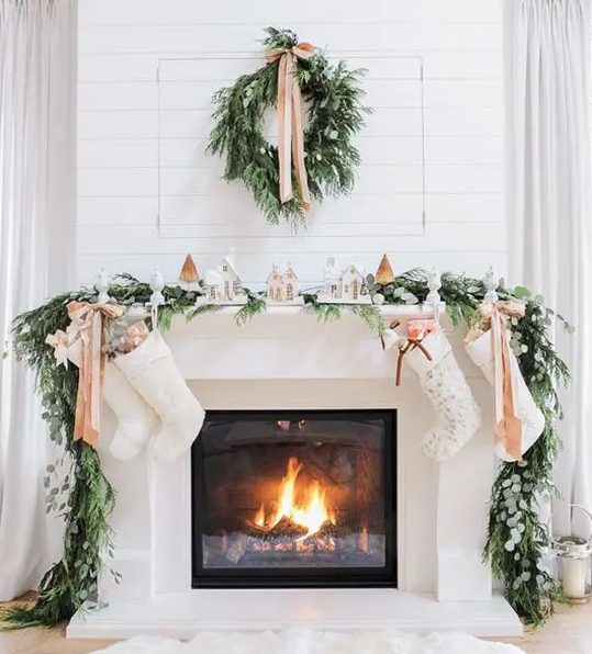 an evergreen wreath and garland, neutral ribbons and a snowy village display will make your mantel look very chic and Christmassy