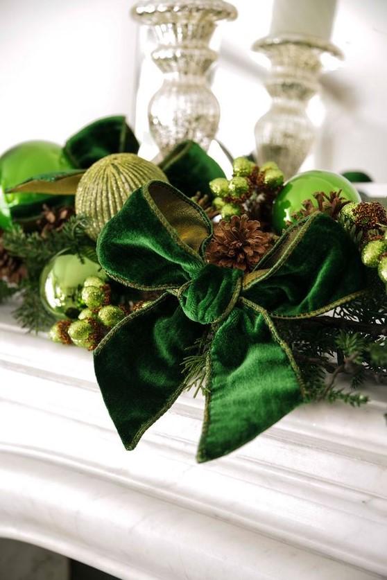 beautiful Christmas decor with light green and green glitter baubles, an emerald velvet bowm pinecones, beads and evergreens