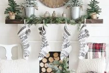 black and white stockings, snowy evergreen trees, an evergreen garland and a wooden Christmas clock for a cozy woodland Christmas look
