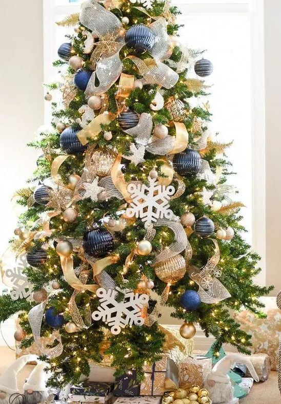 bold Christmas decor with oversized navy and gold ornaments, lights, snowflakes and gold and white ribbons for decor
