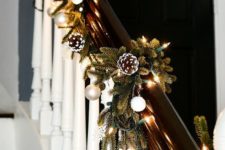 chic railing Christmas decor with lights, evergreens, metallic nd white ornaments is a stylish farmhouse idea
