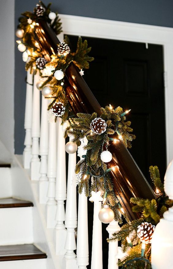 chic railing Christmas decor with lights, evergreens, metallic nd white ornaments is a stylish farmhouse idea