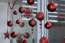 red Christmas ball and snowflake ornaments and beaded garlands to decorate a window