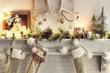some stockings, an evergreen garland with lights, candles and antlers with Christmas ornaments for a super creative Christmas mantel look