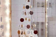 take a large frame, hang some yarn and form a Christmas tree of your favorite ornaments, line it up with lights