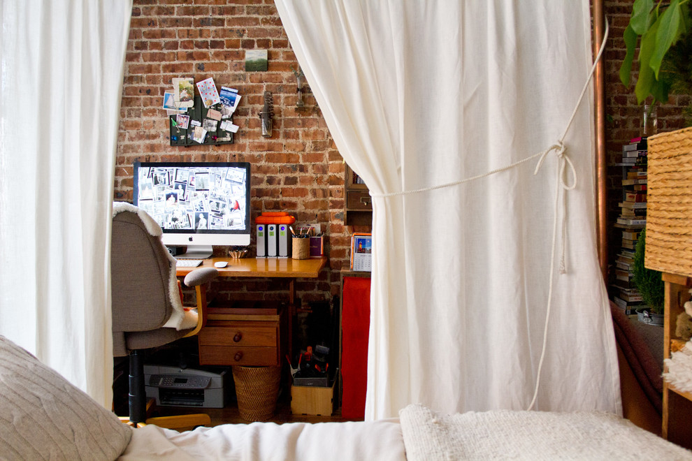 A rugged brick wall and an all-white curtain is a cool mix you could use for a hidden working area in a bedroom.