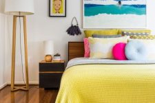 a bold beach inspired bedroom with cool furniture, bright bedding and a bold artwork plus colorful pillows is cool and welcoming