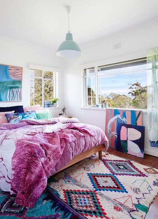 a bold bedroom with a colorful rug, bold bedding and lovely and bold artworks that create a mood in the room
