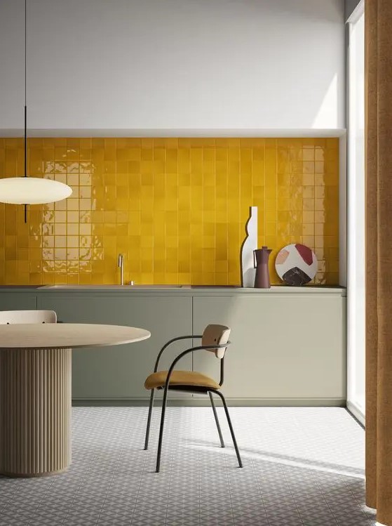 a bold modern kitchen with olive grey cabinetry, a yellow tile backsplash and a refined table and chairs is wow