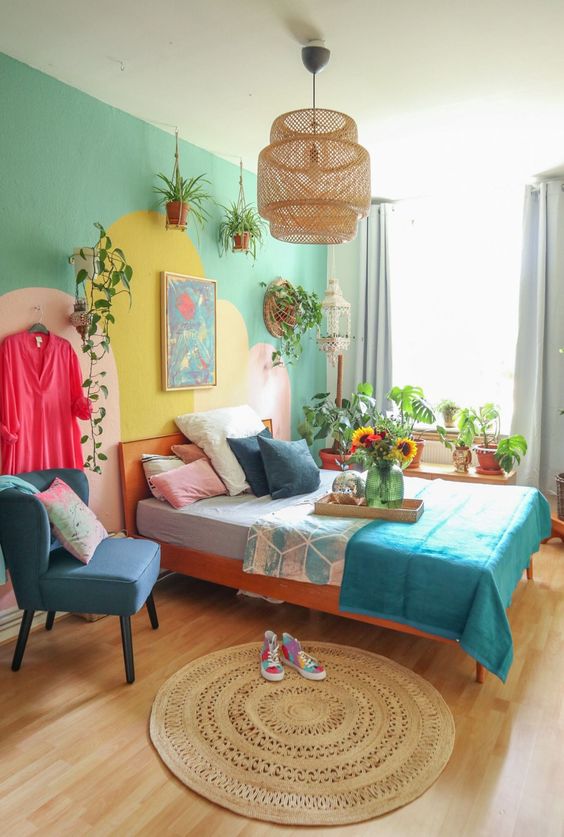 a bright bedroom for a teenager, with a green and yellow accent wall, a stained bed with colorful bedding, a blue chair, potted greenery