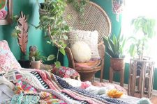 a bright boho bedroom with emerald walls, bold artworks and macrame, colorful bedding and a blanket and lots of potted plants