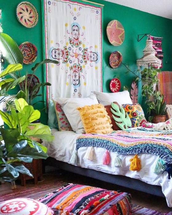 a bright boho bedroom with emerald walls, decorative baskets and colorful artworks, bold textiles and bedding is a real sanctuary