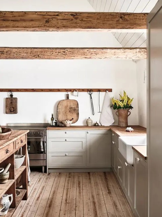 a chic contemporary kitchen in dove grey, with a wooden kitchen island and countertops and rough wooden beams