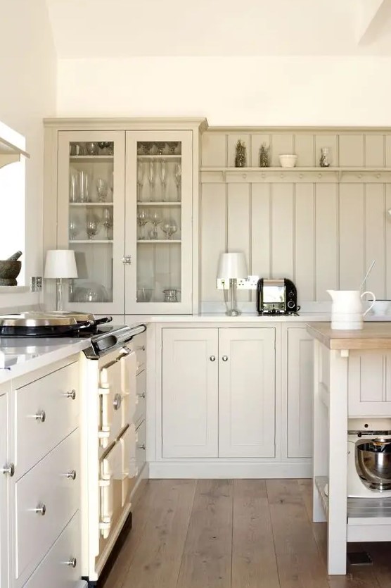 a chic cottage kitchen with tan shaker cabinets and a matching beadboard backsplash plus cool lamps is cozy and cool