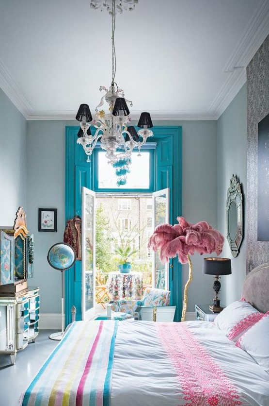 a colorful whimsical bedroom with blue shutters, bright bedding, a feather tree and a mirror dresser with wallpaper inside