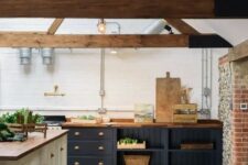 a contemporary barn kitchen with wooden beams, midnight blue cabinets with butcherblock countertops, a white kitchen island and wooden stools